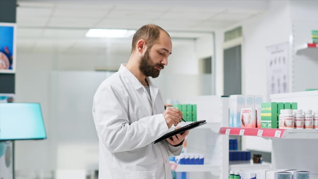Healthcare workers monitoring pharmaceutical packs on racks and managing store inventory to guarantee clients are provided with goods. Pharmacy technician handling pills boxes logistics.