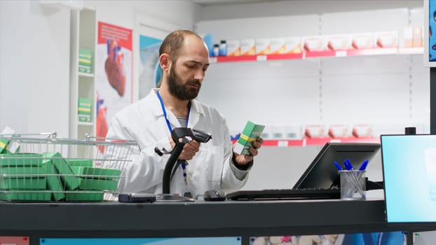 Medical retail clerk scanning supplies to register new stock, working at drugstore checkout counter to ensure medicaments and vitamins inventory. Pharmacist using scanner on pharmaceutics in shop.