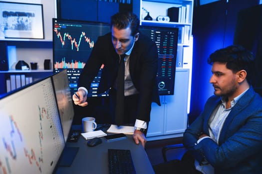 Two stock investors discussing and pointing interesting market stock on monitor. Trend of the technology for dynamic economic investment for planning to select at neon light workplace. Sellable.