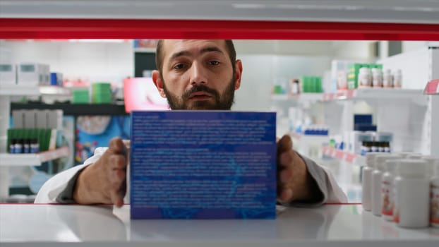 POV of retail worker arranging pharmacy products on shelves, putting stock on display for clients to find any medication. Pharmacist working on organizing medicaments in drugstore. Tripod shot.