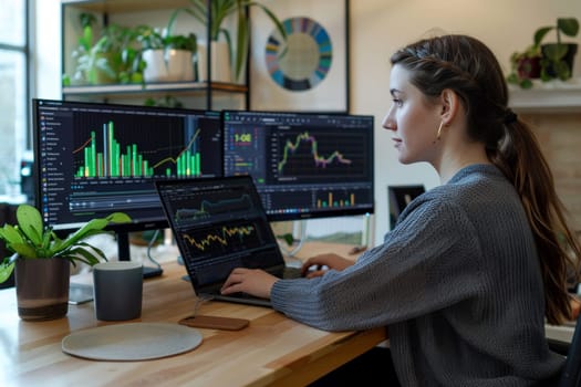 A woman is sitting at a desk with two computer monitors and a laptop.