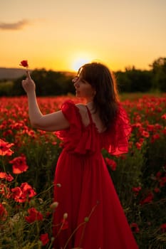 Woman poppy field red dress sunset. Happy woman in a long red dress in a beautiful large poppy field. Blond stands with her back posing on a large field of red poppies.