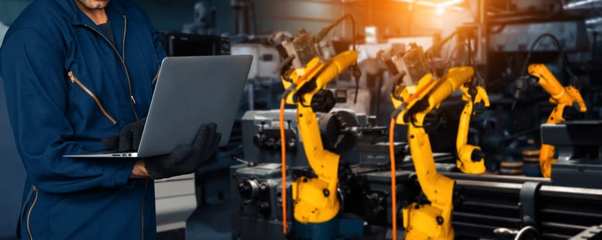 XAI Engineer use advanced robotic software to control industry robot arm in factory. Automation manufacturing process controlled by specialist using IOT software connected to internet network.