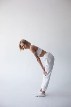 Beautiful blonde girl in a white top and tights posing on a white background. High quality photo