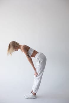 Beautiful blonde girl in a white top and tights posing on a white background. High quality photo