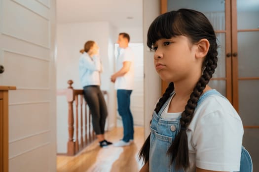 Stressed and unhappy young girl huddle in corner crying and sad while her parent arguing in background. Domestic violence at home and traumatic childhood develop to depression. Synchronos