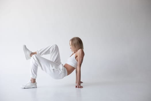 Beautiful blonde girl in a white top and tights posing on a white background. High quality photo