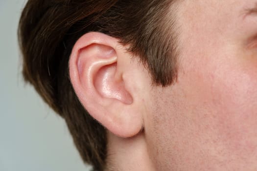 This close-up shot showcases a mans ear and nose in detail. The ear displays its intricate anatomy, including the helix and earlobe. The nose features the nostrils and nasal bridge, capturing the unique texture and contours of the skin.