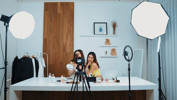 Two influencer partner shoot live streaming vlog video review makeup social media or blog. Happy young girl with vivancy cosmetics studio lighting for marketing recording session broadcasting online.