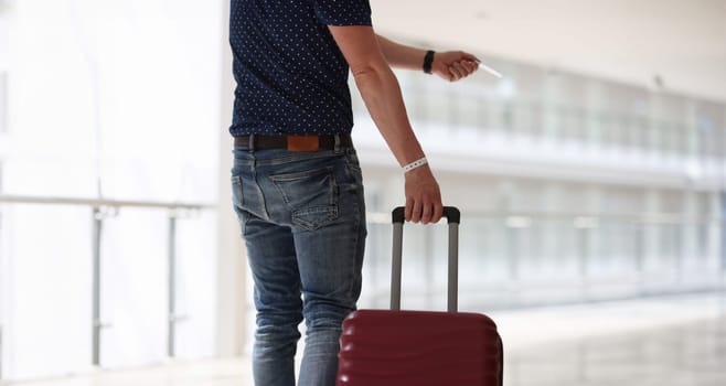 Man with suitcase holding plastic key to hotel room closeup. Safe hotel accommodation concept