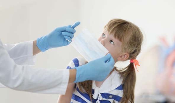 Doctor putting protective medical mask on little girl in clinic. Prevention covid19 mask mode concept