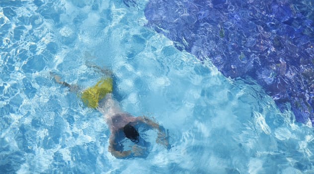 Young man lying on bottom of swimming pool top view. Drowning aid concept