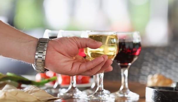 Man hand taking glass of white wine in restaurant closeup. Degustation of wines concept