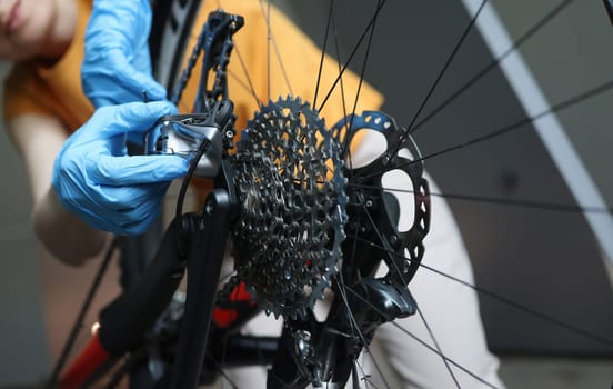 Craftsman in rubber protective gloves repairing bicycle closeup. Bicycle service concept