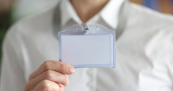 Woman holding blank badge in hand closeup. Personal identification at business conferences concept