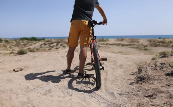 Man holding bike on sand near sea closeup. Achievements of goals concept