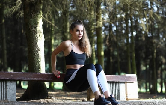 Girl doing stretching muscles leaning on bench. Girl increases working capacity learns to use for all her energy. Incorrect exercises lead to sprains and muscle pains, to increased fatigue.