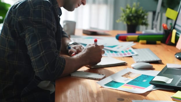 Close up of smart business man hand choosing color palettes while sitting at meeting table with note. Aerial view of interior designer design and select color theme by using color palettes. Symposium.