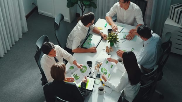 Professional smart business team discussing about using clean energy and sustainable investment at meeting table with wind mill, document with environmental graph and wooden house model. Alimentation.