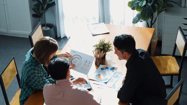 Top view of diverse business team explain marketing idea to investor while manager hold laptop and going for taking a break. Group of creative people explain financial graph at meeting. Convocation.