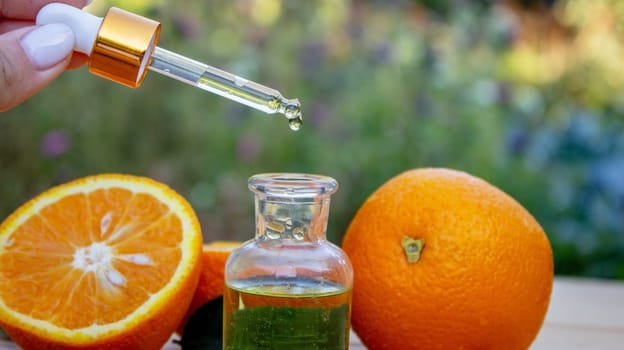 bottle of aromatic essence and fresh orange on the background of nature