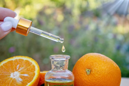 bottle of aromatic essence and fresh orange on the background of nature