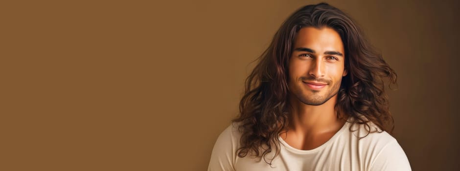 Portrait of an elegant sexy smiling Latino man with perfect skin and long hair, on a beige background. Advertising of cosmetic products, spa treatments shampoos and hair care products, dentistry and medicine, perfumes and cosmetology for men