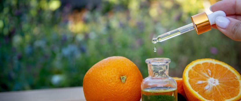 bottle of aromatic essence and fresh orange on the background of nature