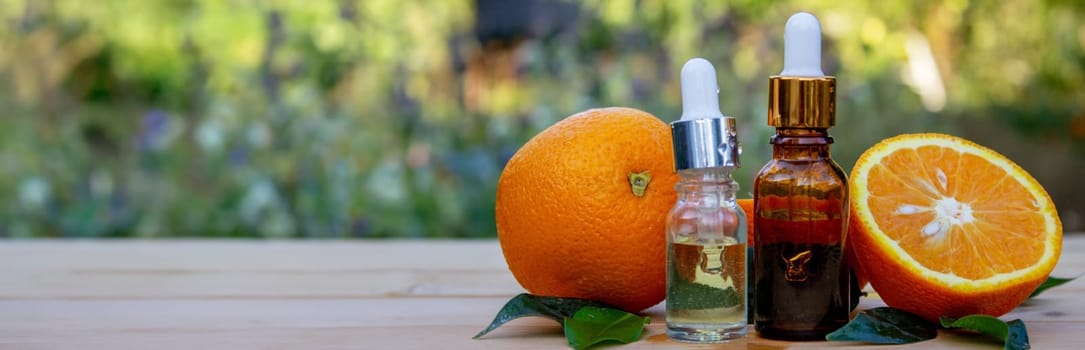 bottle of aromatic essence and fresh orange on the background of nature