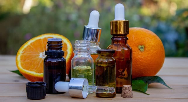 bottle of aromatic essence and fresh orange on the background of nature