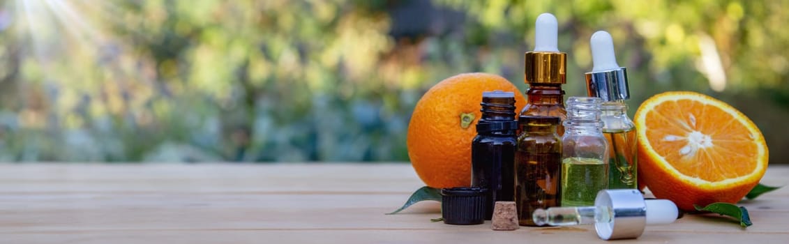 bottle of aromatic essence and fresh orange on the background of nature