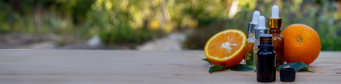 bottle of aromatic essence and fresh orange on the background of nature