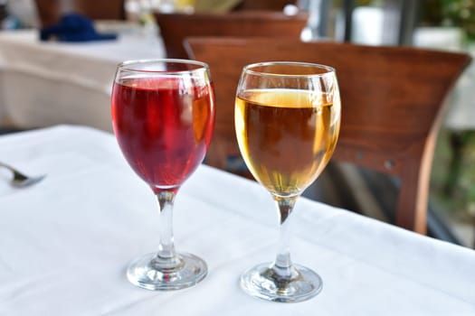 Two glasses with red and white wine stand on table