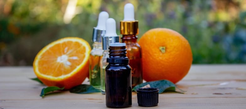 bottle of aromatic essence and fresh orange on the background of nature