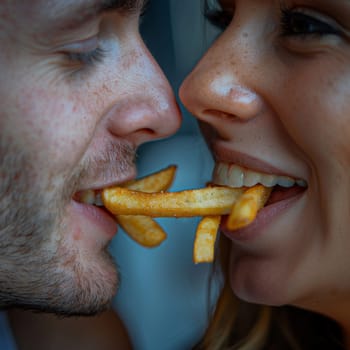 Close up of young couple sharing french fries.