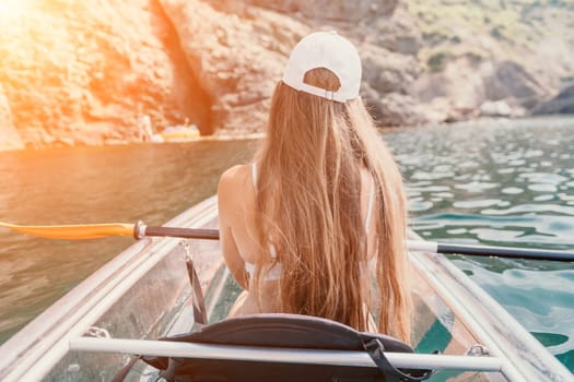 Woman in kayak back view. Happy young woman with long hair floating in transparent kayak on the crystal clear sea. Summer holiday vacation and cheerful female people having fun on the boat.