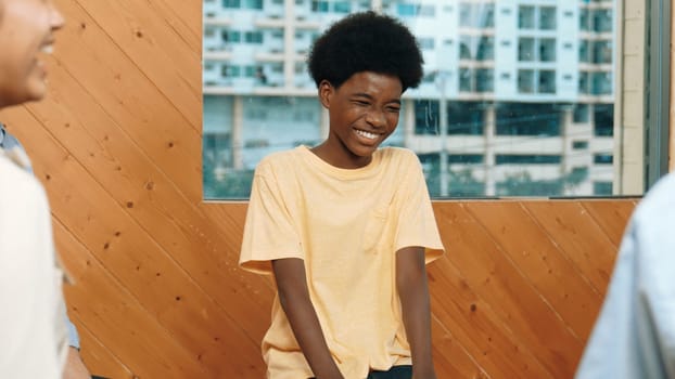 Smiling african boy sitting in circle while listening diverse friend sharing idea in group therapy with trust. Highschool student thinking and learning about mental health problem. Edification.