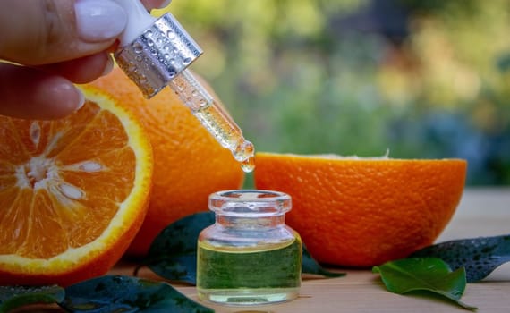 bottle of aromatic essence and fresh orange on the background of nature