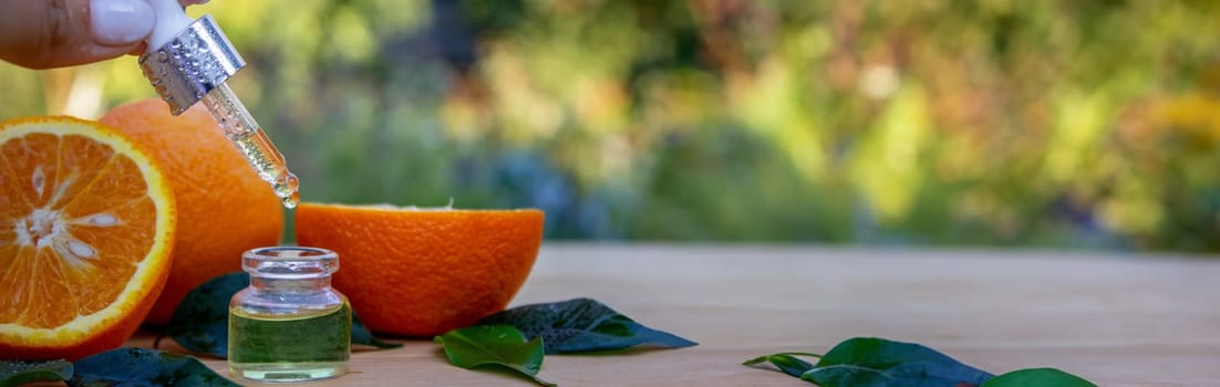 bottle of aromatic essence and fresh orange on the background of nature