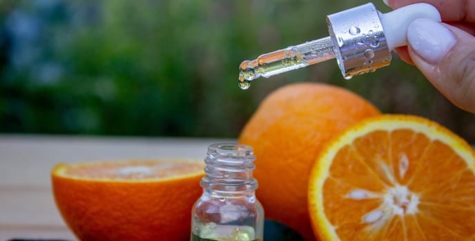 bottle of aromatic essence and fresh orange on the background of nature