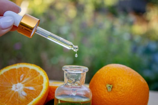 bottle of aromatic essence and fresh orange on the background of nature