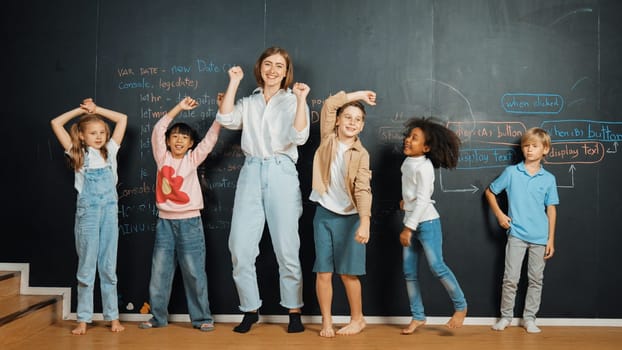 Multicultural happy student and teacher smiling and standing at blackboard with engineering code or prompt written. Kid express feeling of happy and enjoy with studying in STEM classroom. Erudition.