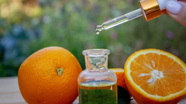 bottle of aromatic essence and fresh orange on the background of nature