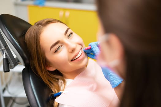 Dentist uses interdental brush for perfect clean teeth at clinic to young woman at the clinic
