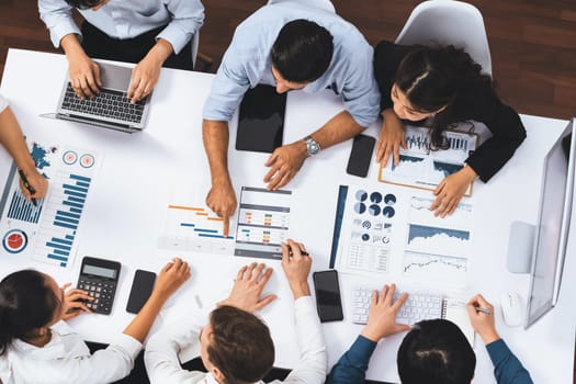 Top view analyst team utilizing BI Fintech to analyze financial data at table in meeting room. Analytic BI dashboard power on paper for business insight and strategic marketing planning. Prudent