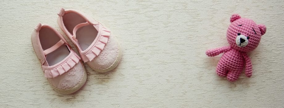 Children's shoes and teddy bear on a light background. Background with place for text.