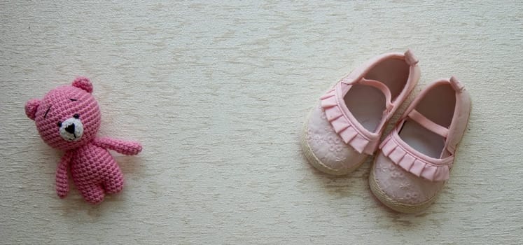 Children's shoes and teddy bear on a light background. Background with place for text.