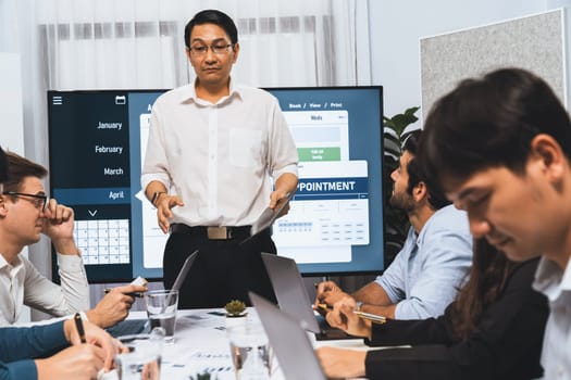 Project manager communicate and collaborate with team using project management software display on monitor, tracking progress of project task and making schedule plan at meeting table. Prudent