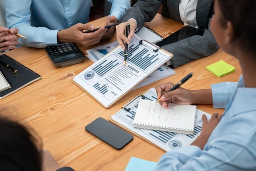 Multiracial analyst team use BI dashboard data to analyze financial report on meeting table. Group of diverse business people utilize data analysis by FIntech for business marketing decision. Concord