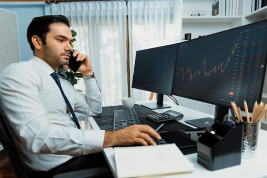 Trader businessman calling to consultant or partner with two stock exchange investment, compare data analysis to invest high profit value dynamic financial technology stock market at office. Surmise.